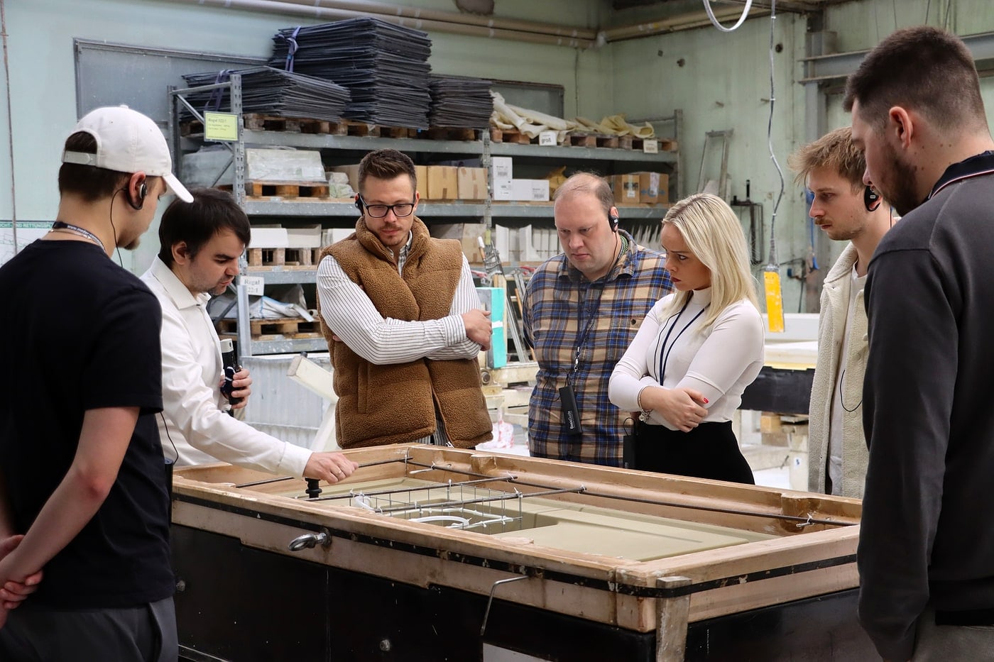 Werksführung beim Herstellerbesuch: Gruppe junger Küchenunternehmer in der Produktion
